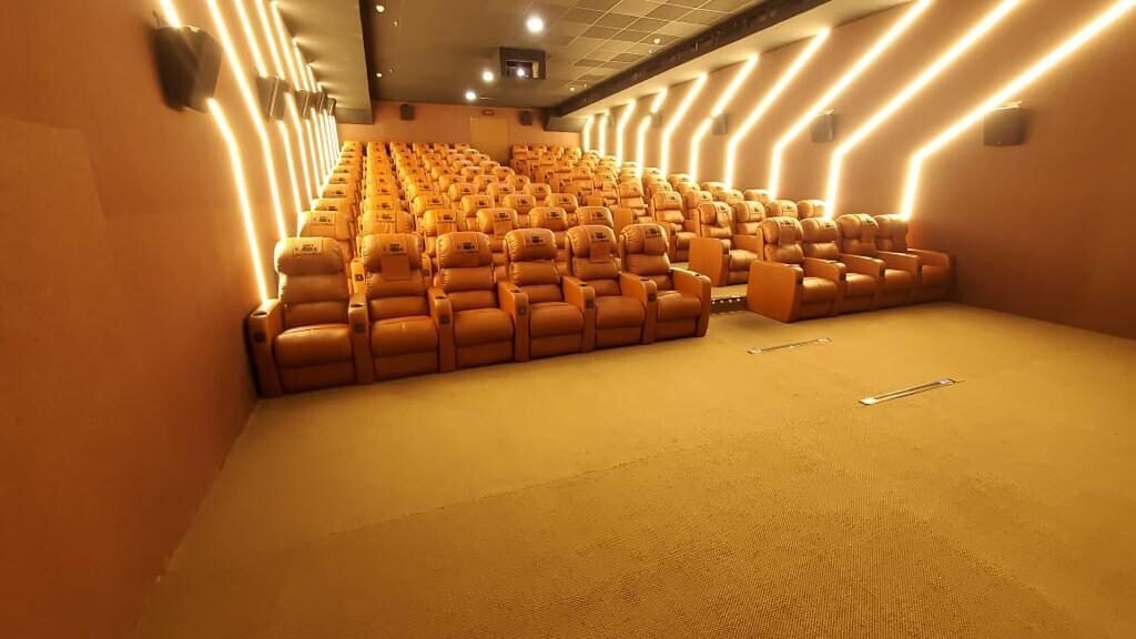 Tan leather recliners rising in tiers beneath gold chevron wall lighting