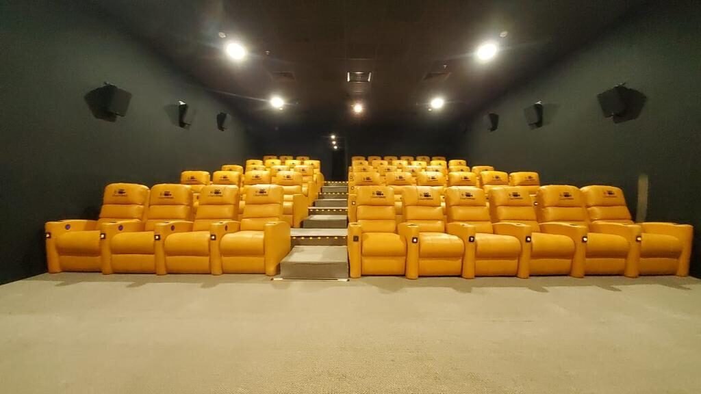 Two banks of saffron leather Cineverse recliners either side of a lit centre aisle