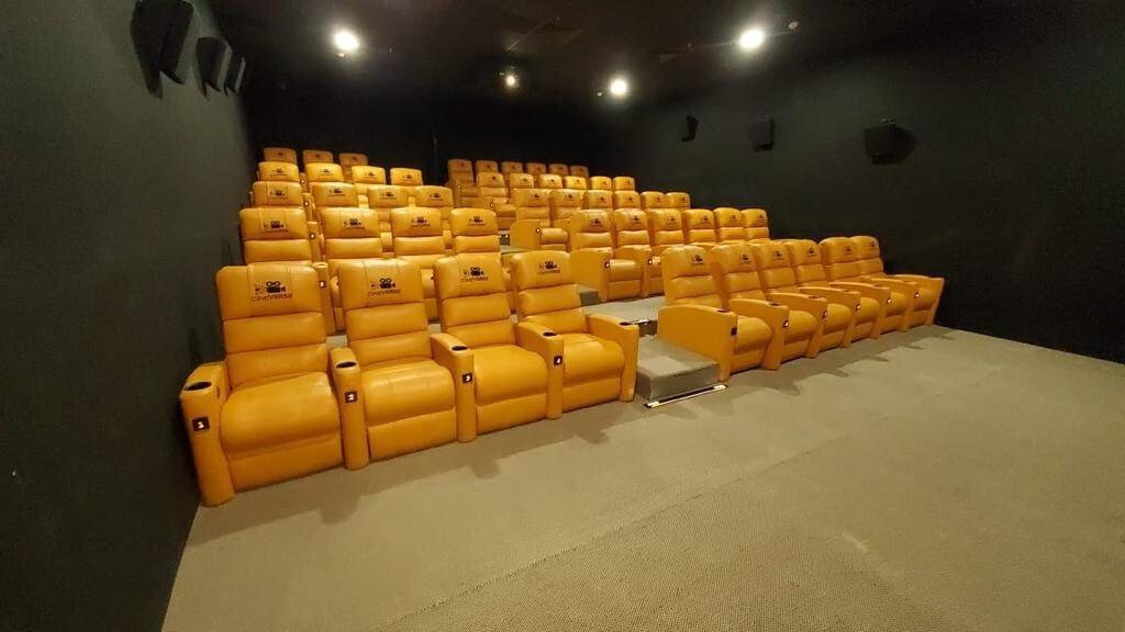 Stadium-tiered saffron recliners in a Cineverse auditorium