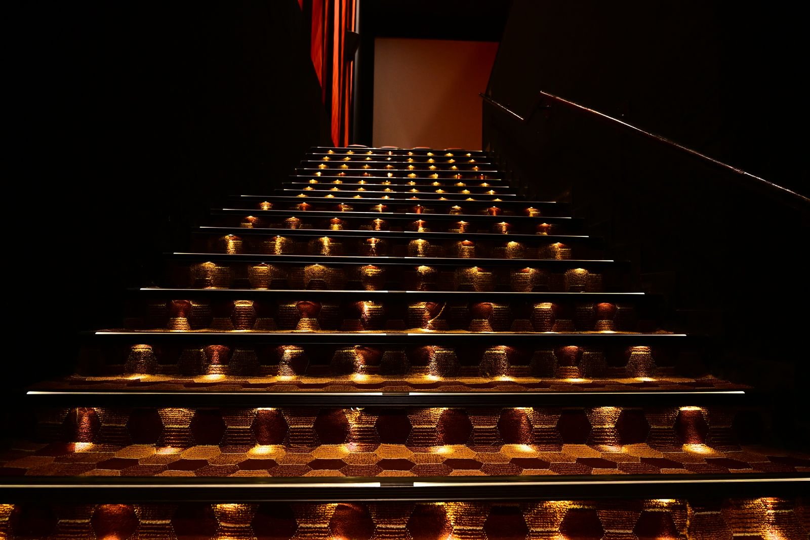 Illuminated step nosings guiding the way up a darkened Cineverse Multiplex aisle